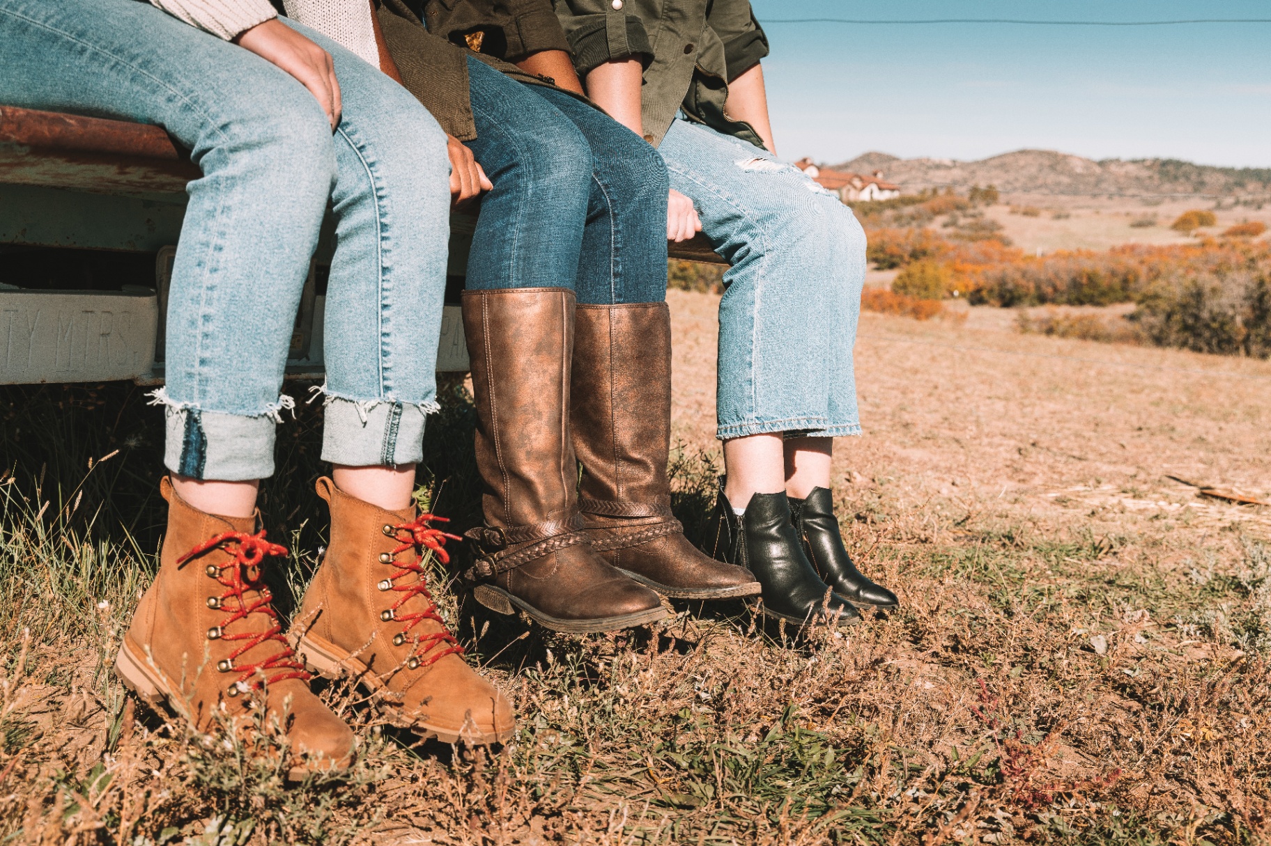 Three young women sitting on the back of a vintage truck in the Colorado foothills